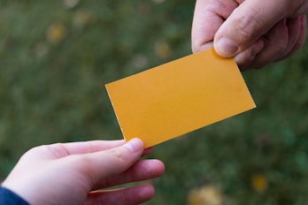 Close-up of hands exchanging business cards with marketing materials in the background.