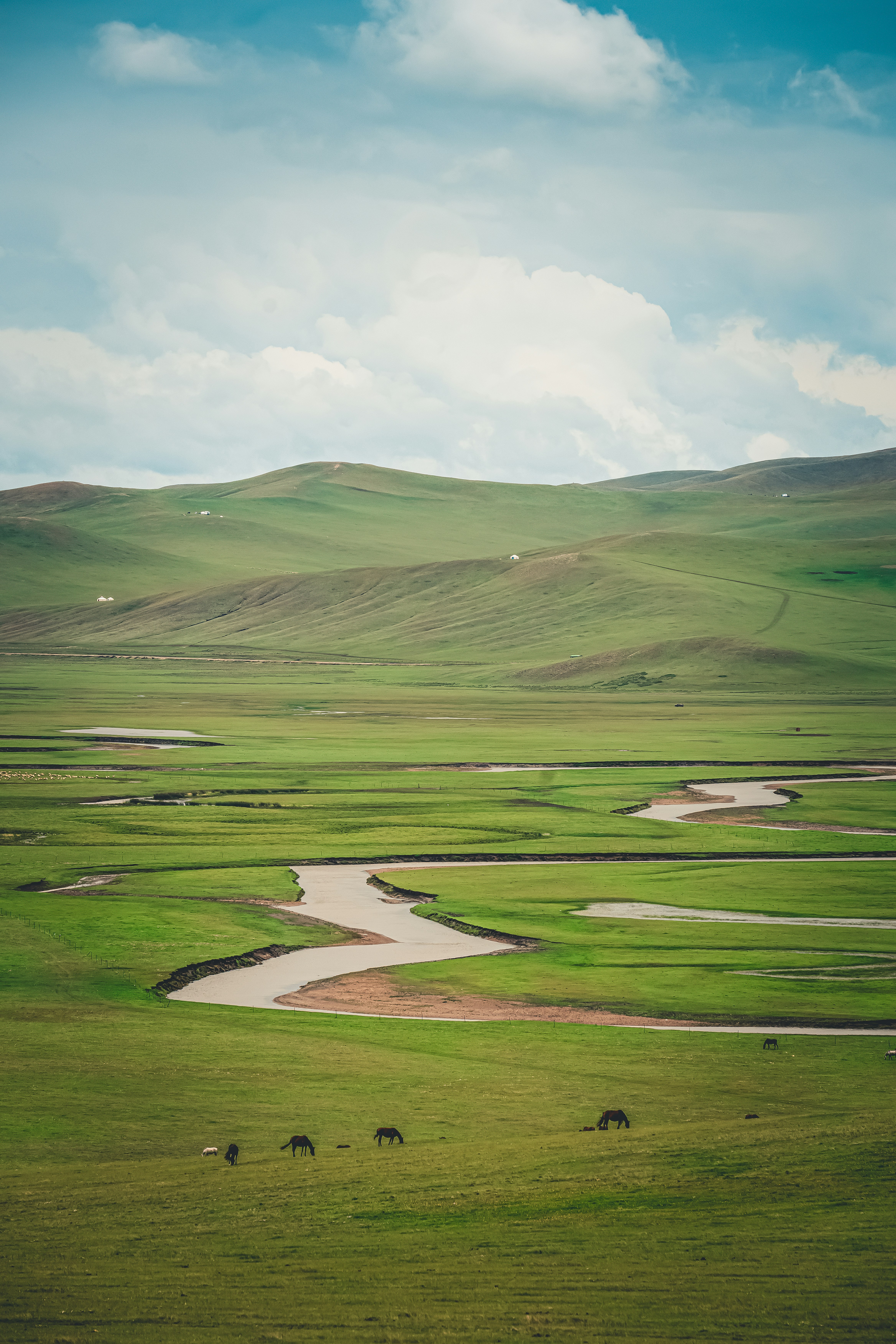 a wide open field with a river running through it
