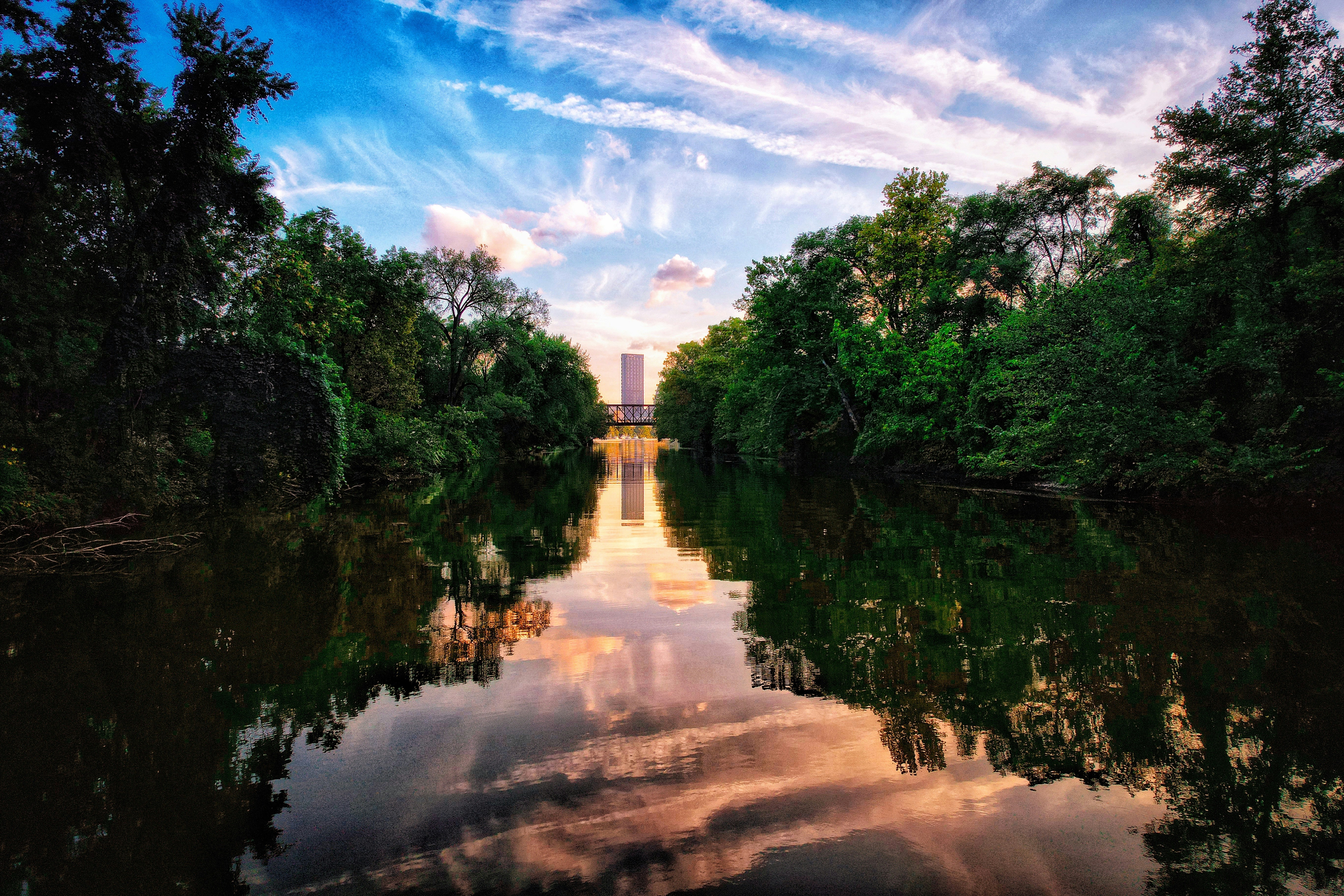a body of water surrounded by trees and clouds