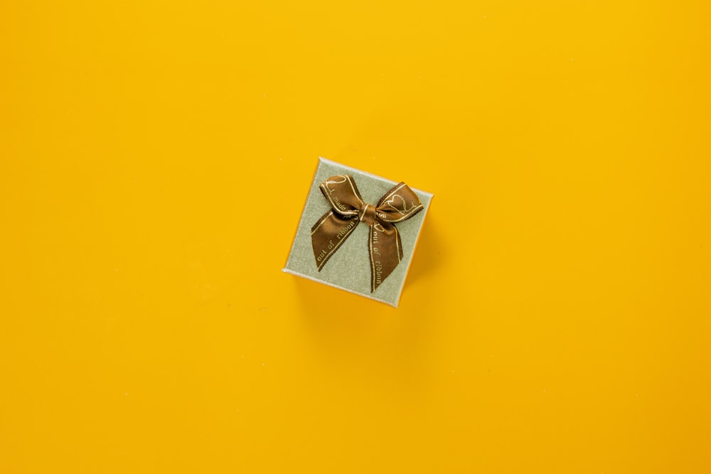 a gift box with a brown bow on a yellow background