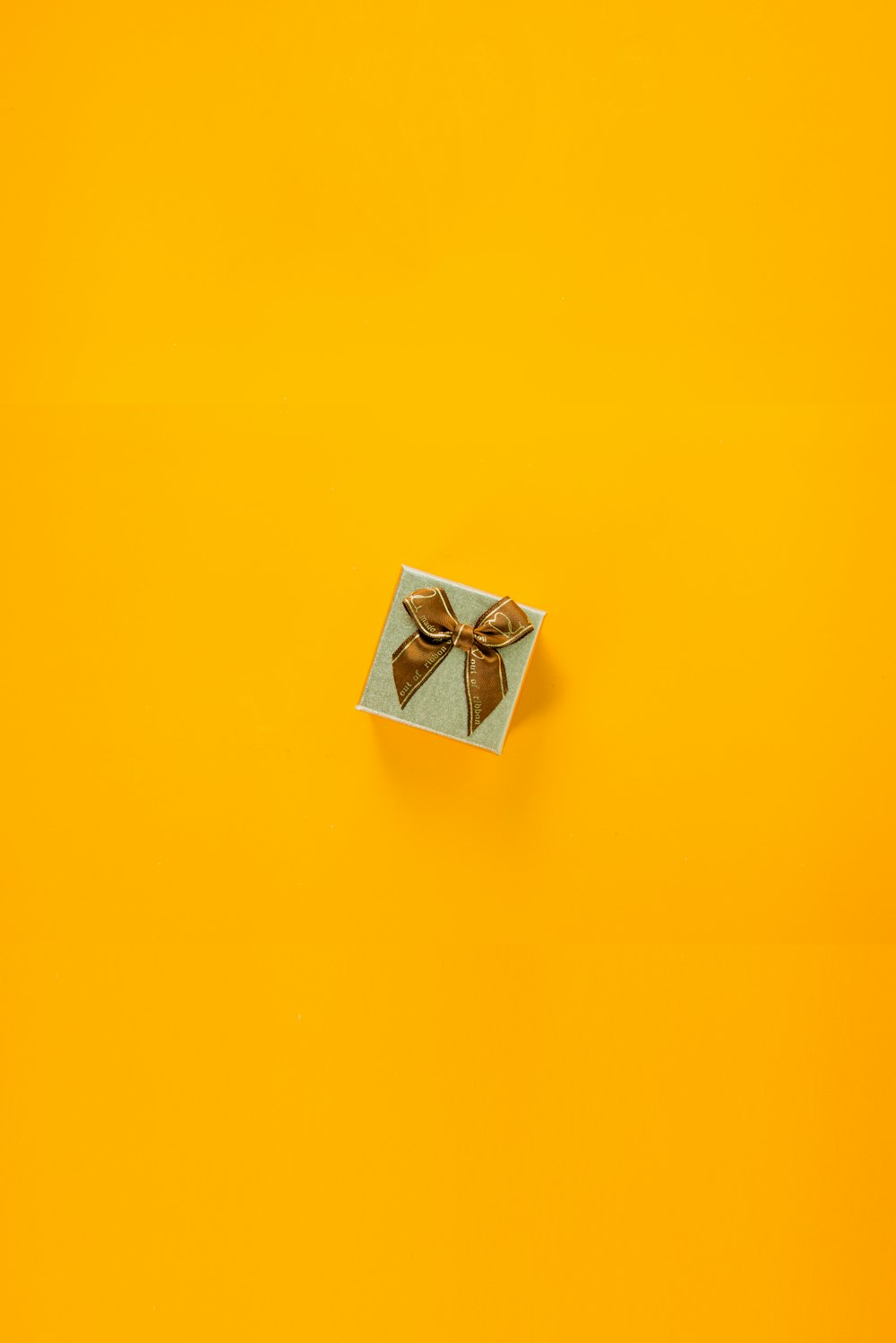 a box with a bow on a yellow background