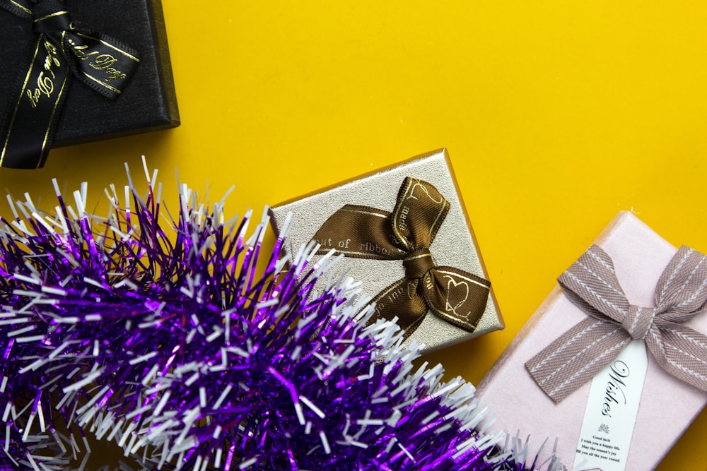 a gift wrapped in gold and silver ribbon next to a purple tinsel
