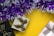 Several gift boxes with ribbon bows, placed on a bright yellow background, surrounded by purple and white tinsel.