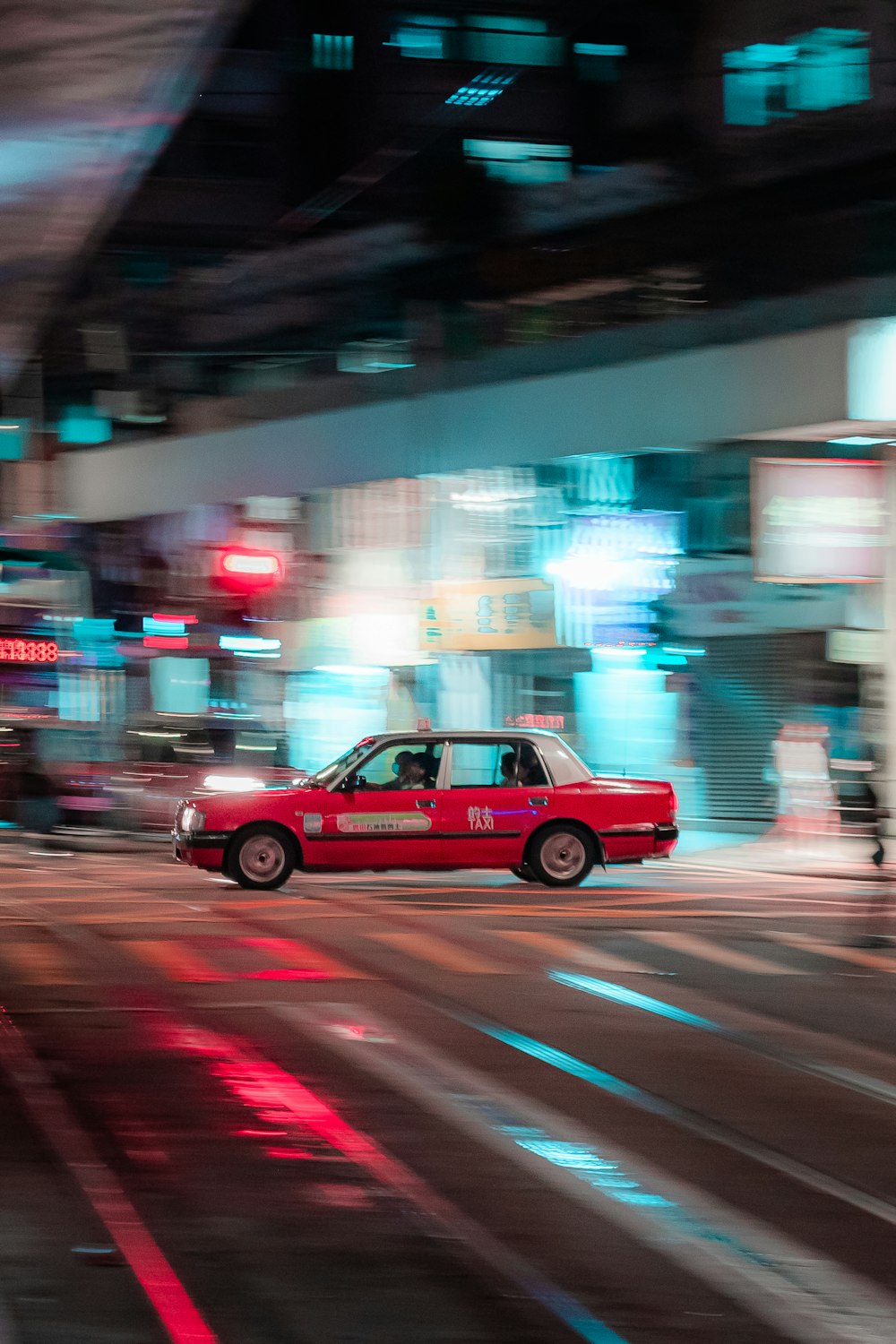 a red taxi cab driving down a street next to tall buildings