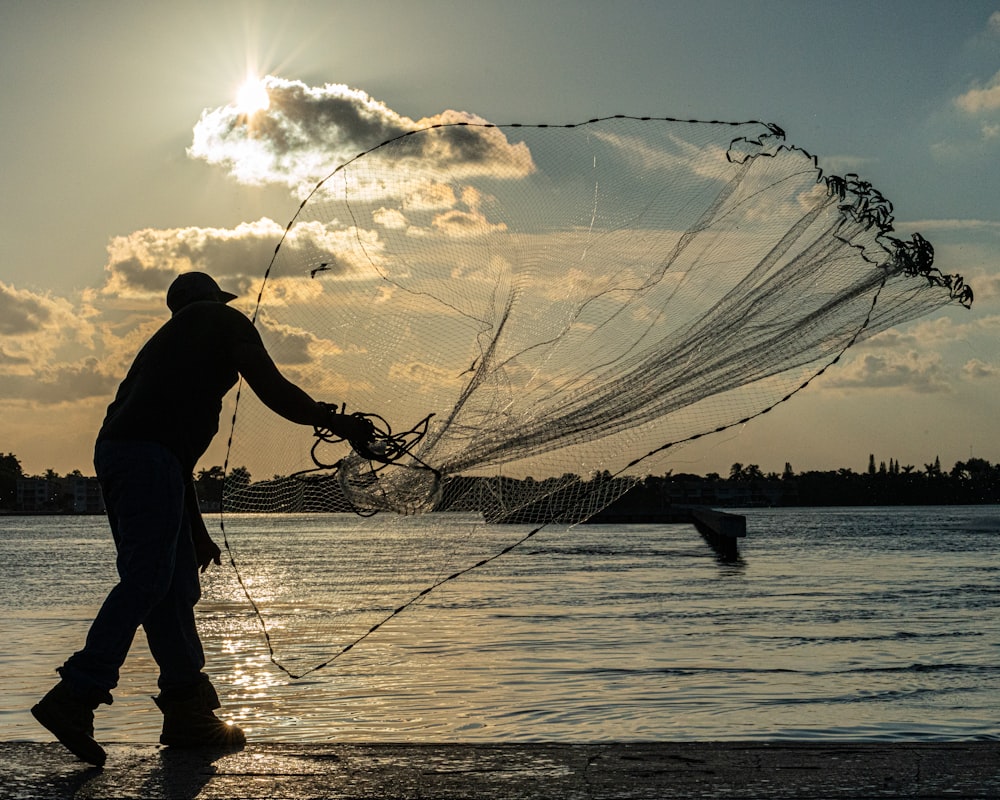 a man standing on a beach holding a fishing net