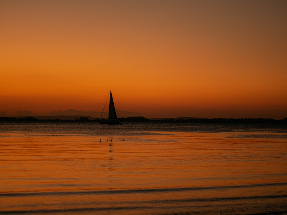 a sailboat on the water at sunset