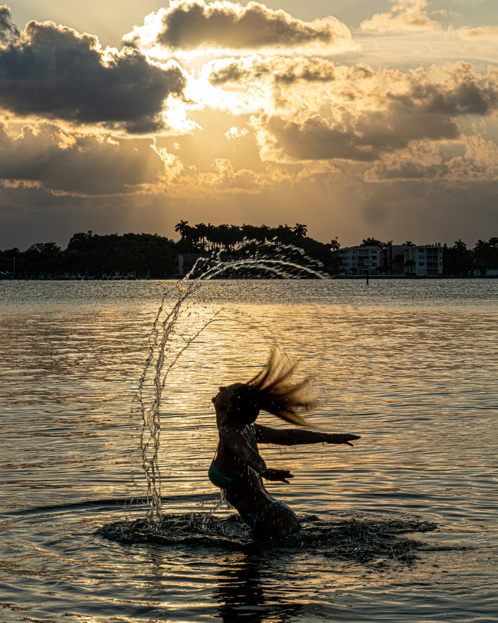 a woman in the water spraying water on her head