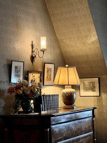 A cozy corner featuring a hand-painted vintage dresser with delicate floral patterns and a softly glowing lamp.