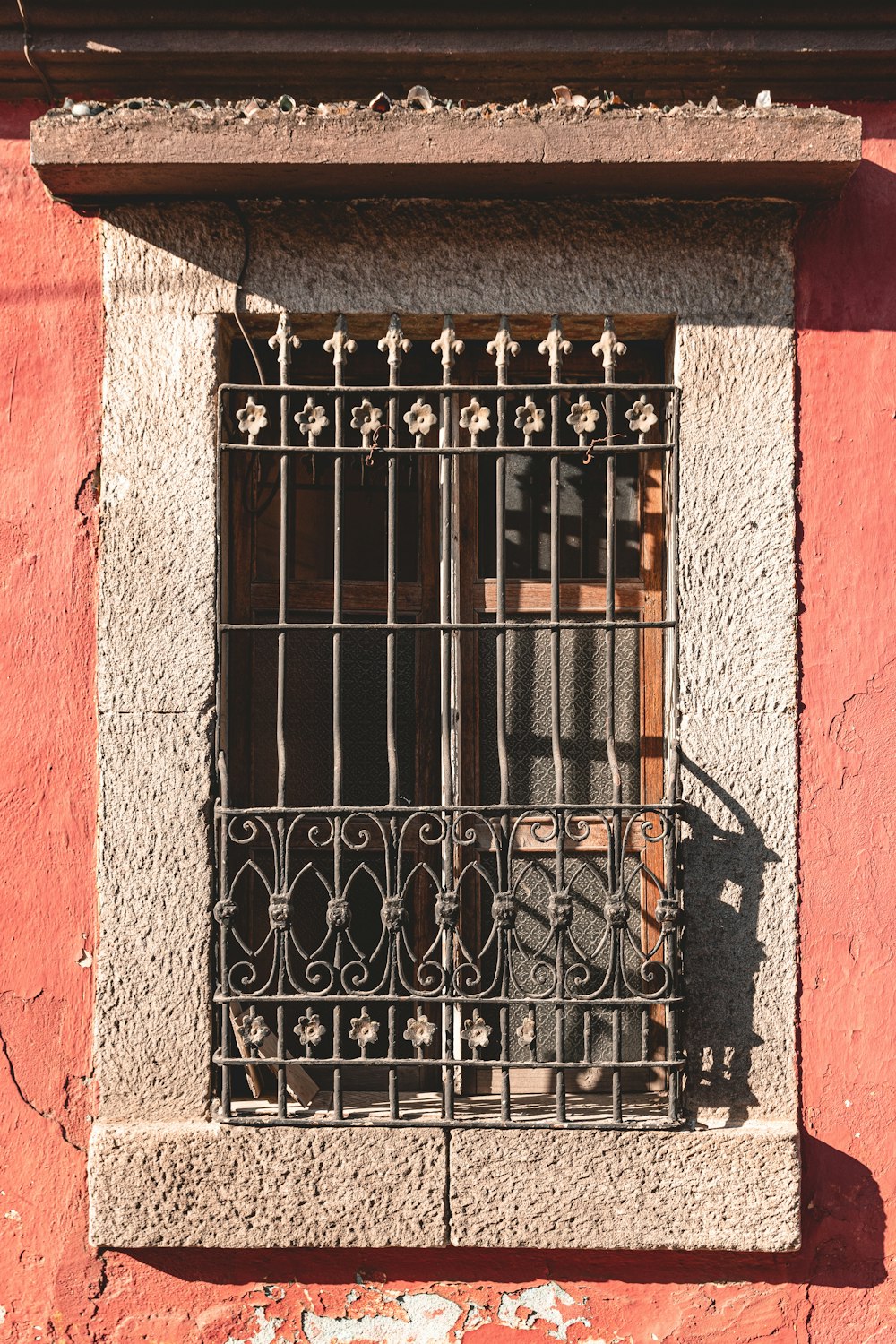a red building with a window and iron bars