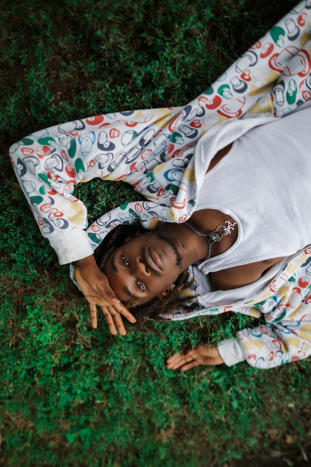 a young girl laying on the ground in the grass