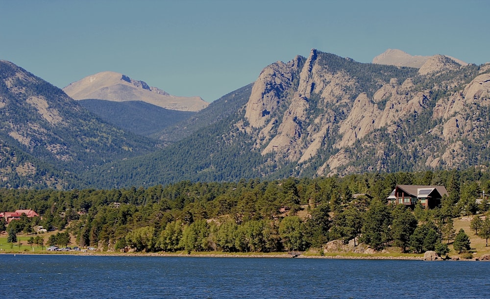 a lake with mountains in the background and a cabin in the foreground