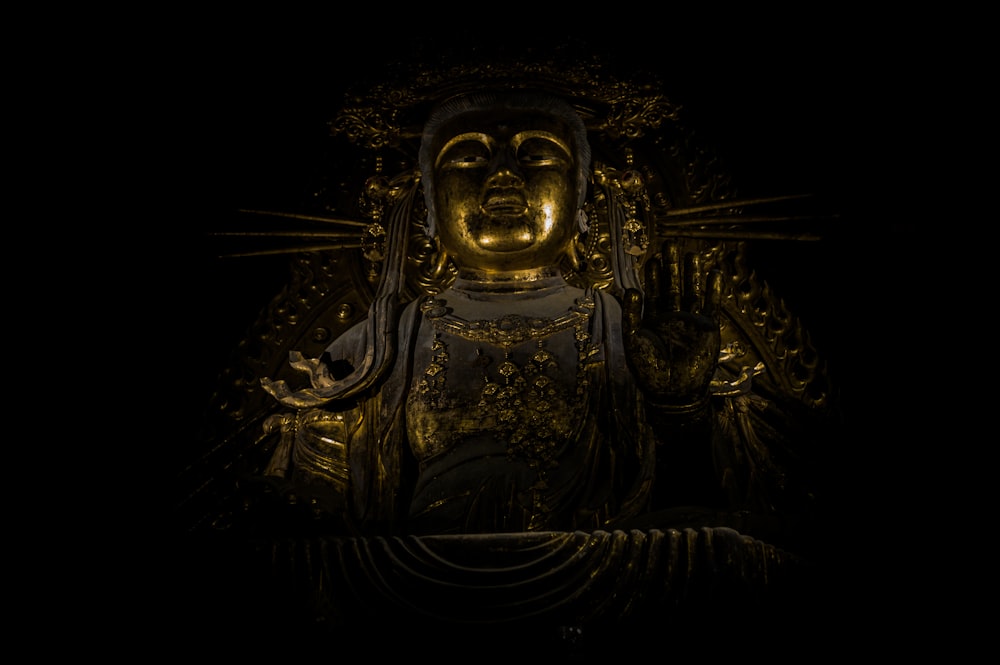 a golden buddha statue in a dark room