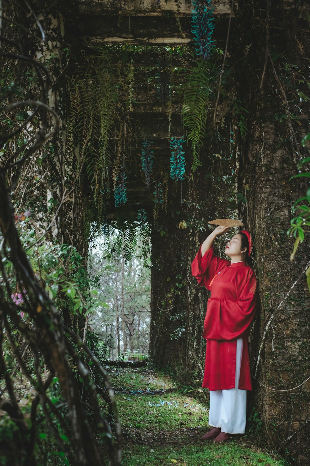 a woman in a red dress standing in a forest