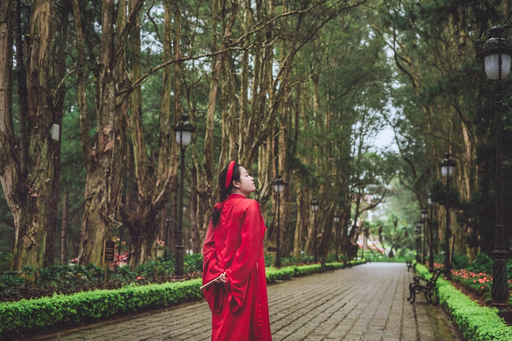 a woman in a red robe standing on a brick road