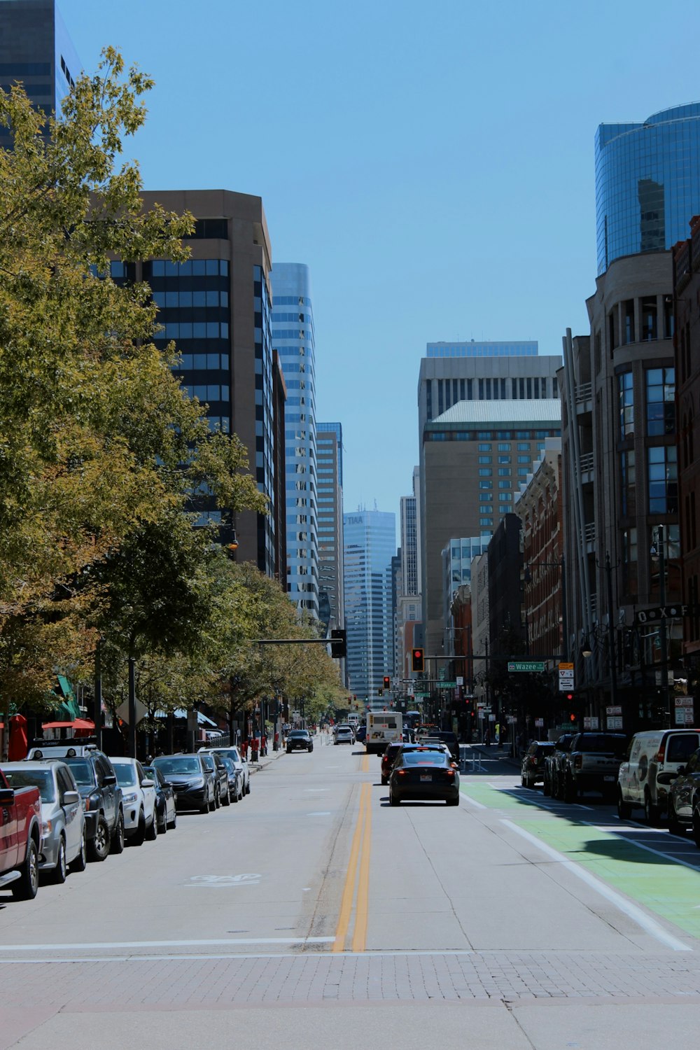 a city street lined with parked cars and tall buildings