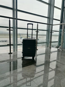 Close-up of a sleek black suitcase with gold accents on a polished marble floor.