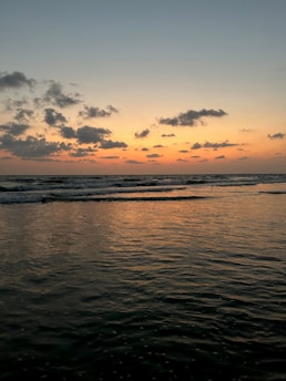 A serene sunset over gentle ocean waves, reflecting calming muted green and blue tones.