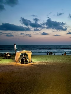 A cozy beachfront cabana at sunset with soft lighting and calm waves.