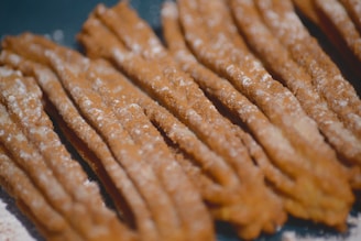 Close-up of golden churros dusted with cinnamon sugar on a rustic plate.