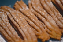 Close-up of golden churros dusted with sugar, served with a pink dipping sauce.
