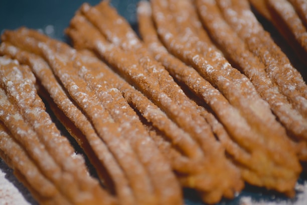 Close-up of golden, crispy churros dusted with cinnamon sugar on a rustic wooden table