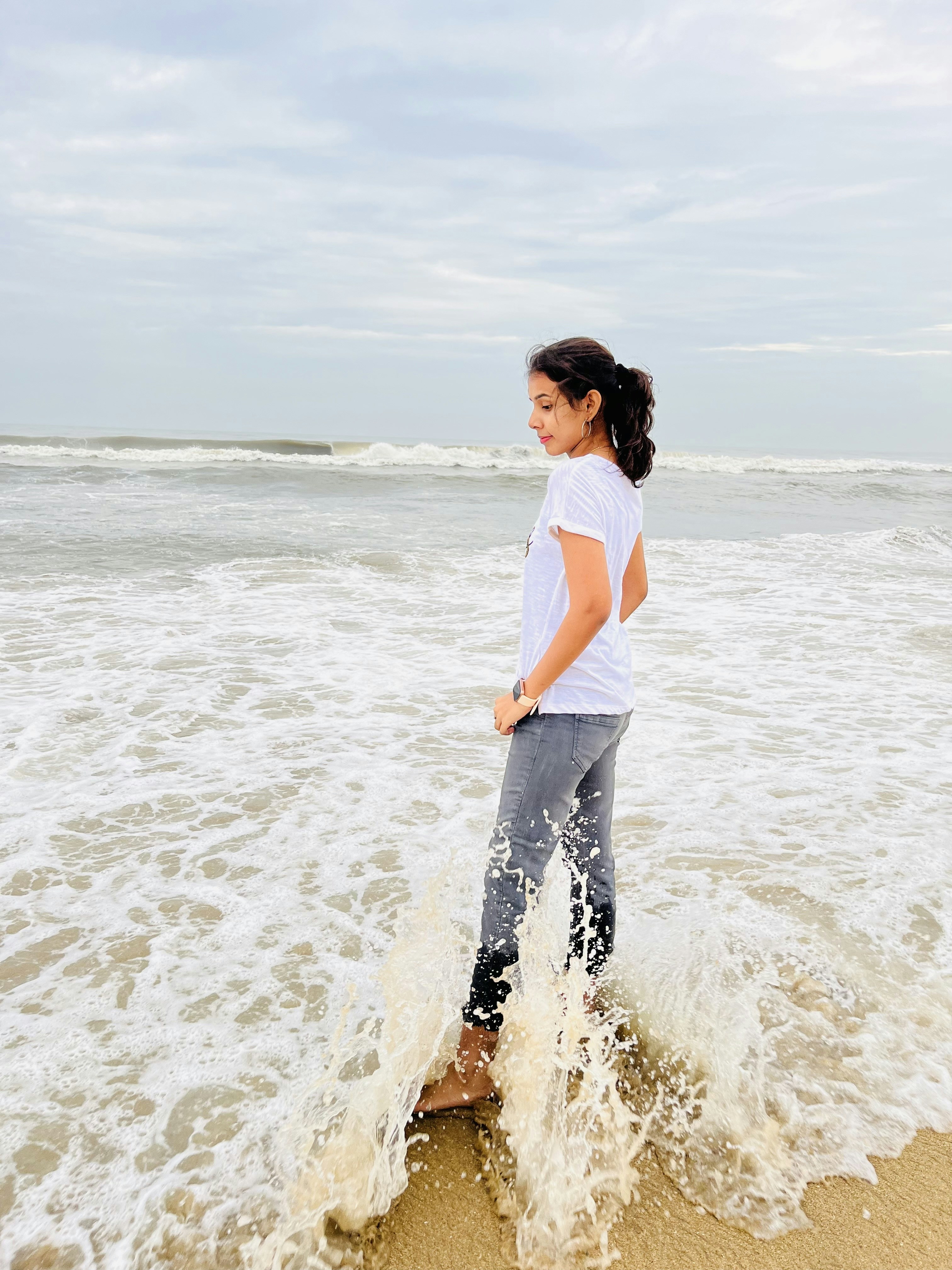 a woman standing in the surf at the beach