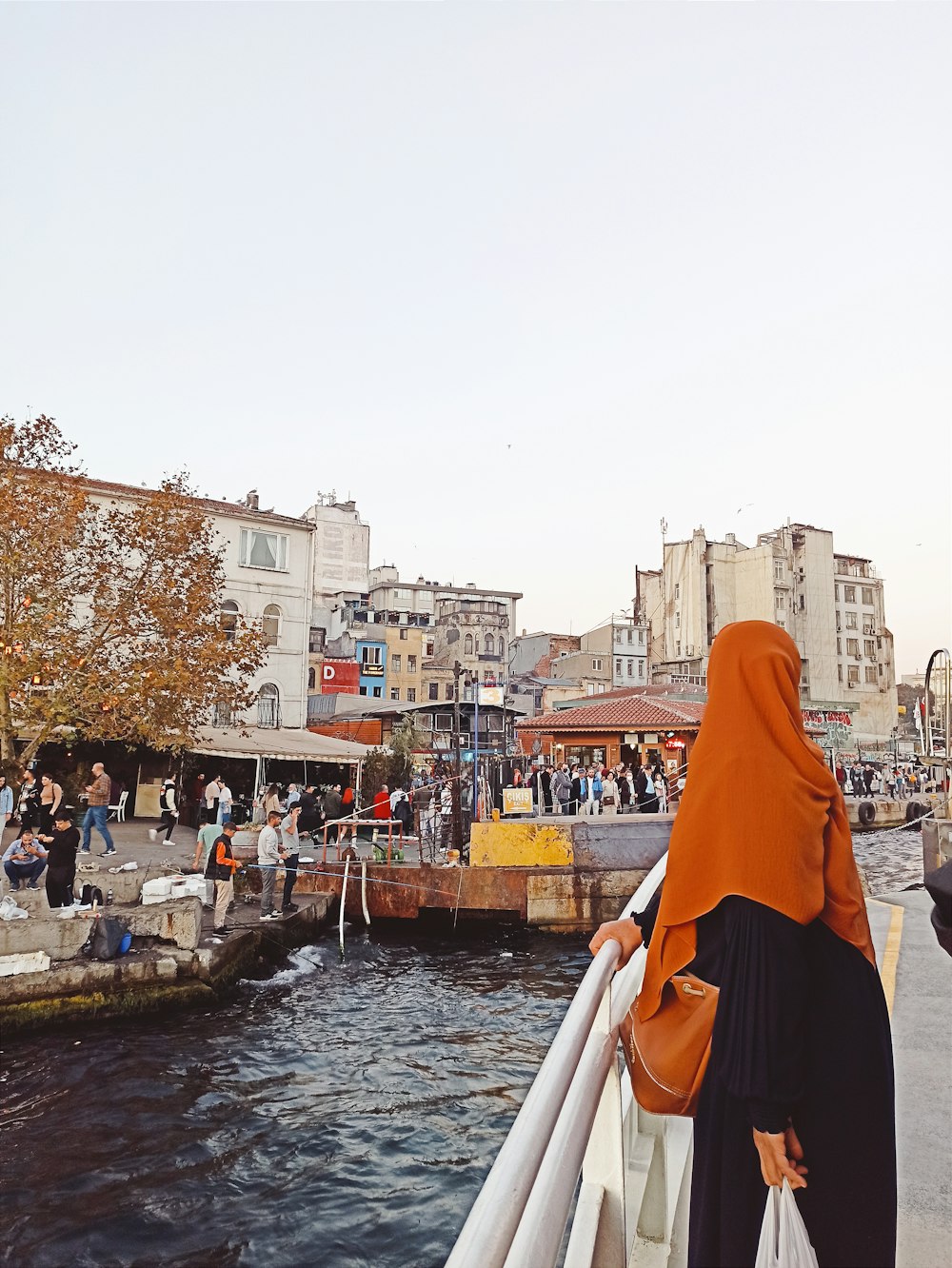 a woman in an orange hijab is looking out over the water