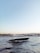 A sleek, modern yacht is gliding through a body of water with gentle waves. In the background, a cityscape featuring historic architecture, including minarets and domes, can be seen under a clear blue sky, creating a serene and picturesque scene.