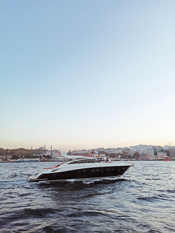 A sleek yacht cutting through gentle Mediterranean waves under a clear blue sky near Herzliya Marina.