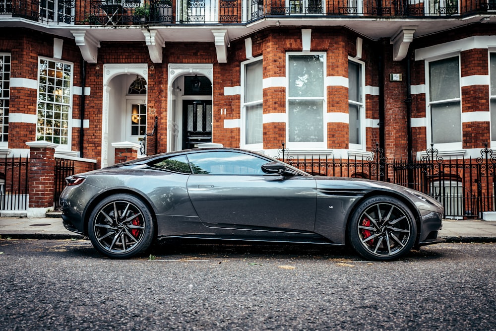 a grey sports car parked in front of a brick building
