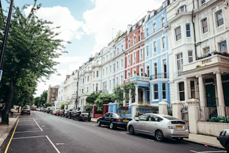A friendly agent handing over keys to happy tenants outside a charming UK townhouse.