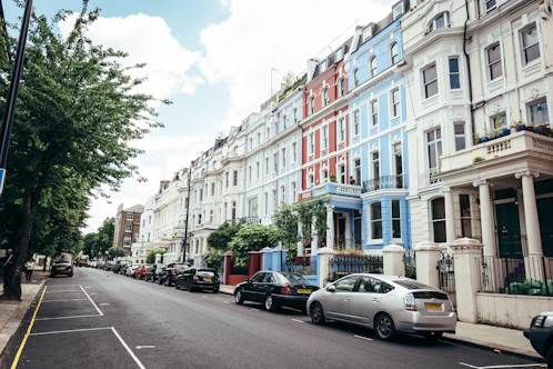 A friendly agent handing over keys to happy tenants outside a charming UK townhouse.