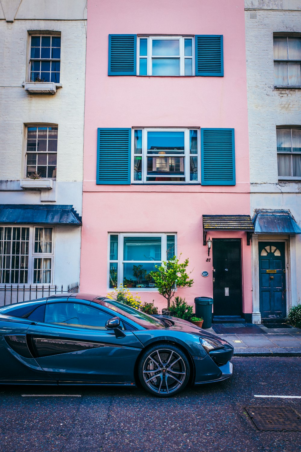 a blue sports car parked in front of a pink building