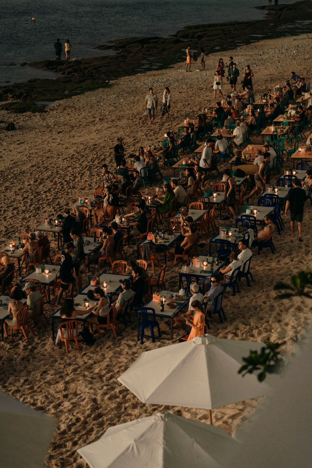 a group of people sitting at tables on a beach