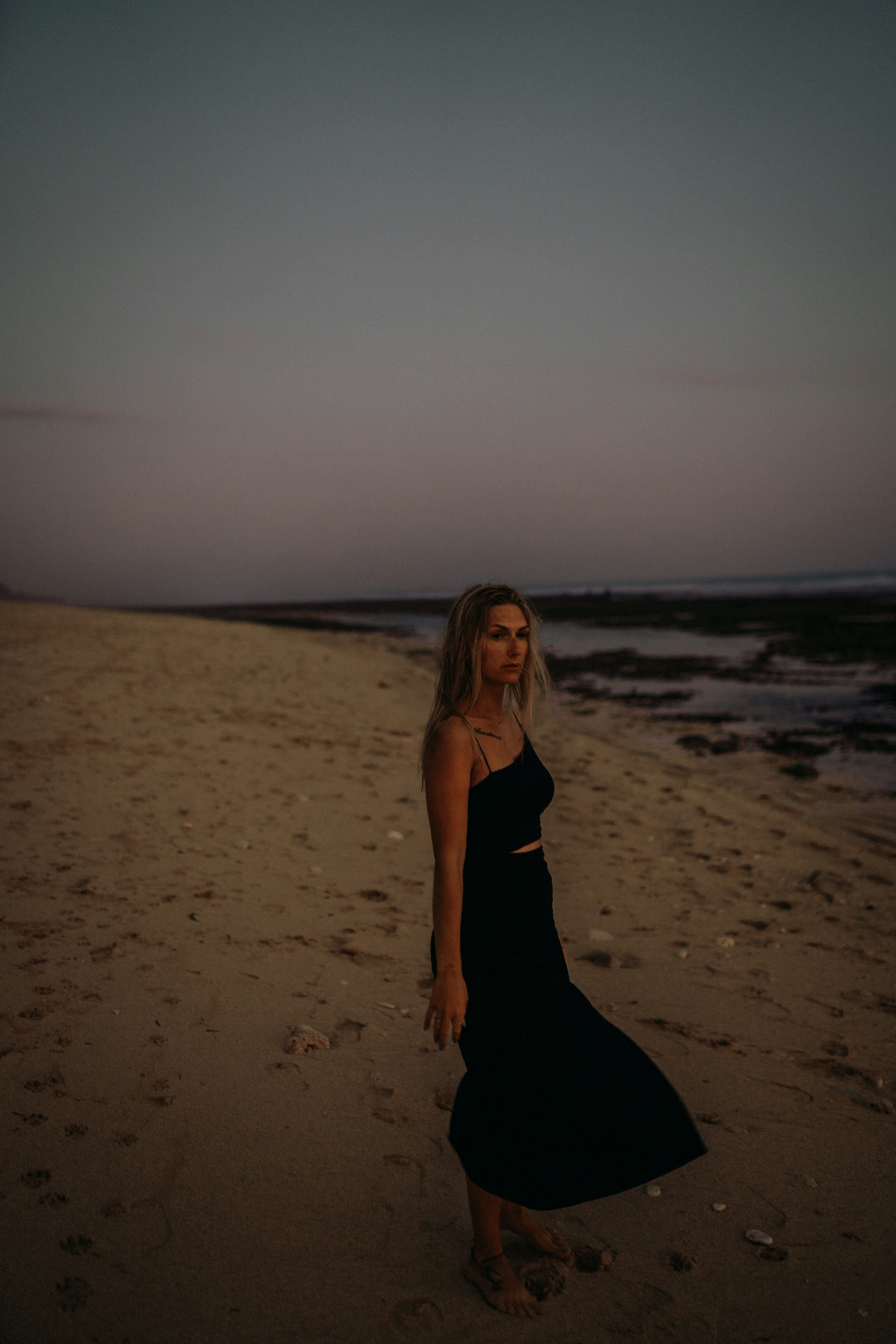 a woman in a black dress standing on a beach