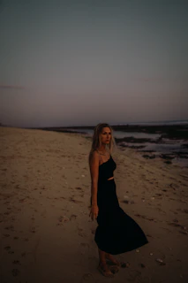 Elegant woman in a nude bikini standing on a sandy beach at sunset