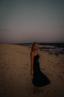 Elegant woman in a nude bikini standing on a sandy beach at sunset