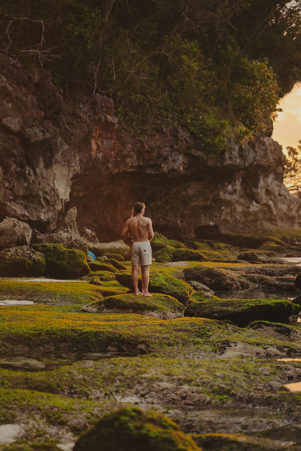 a man standing on a rocky beach next to a body of water