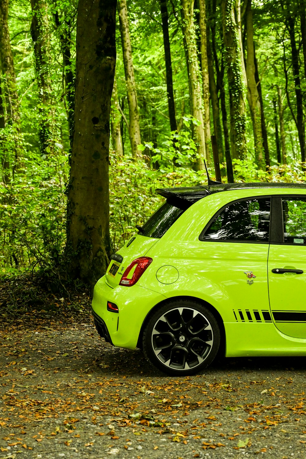 une voiture vert vif garée dans une zone boisée