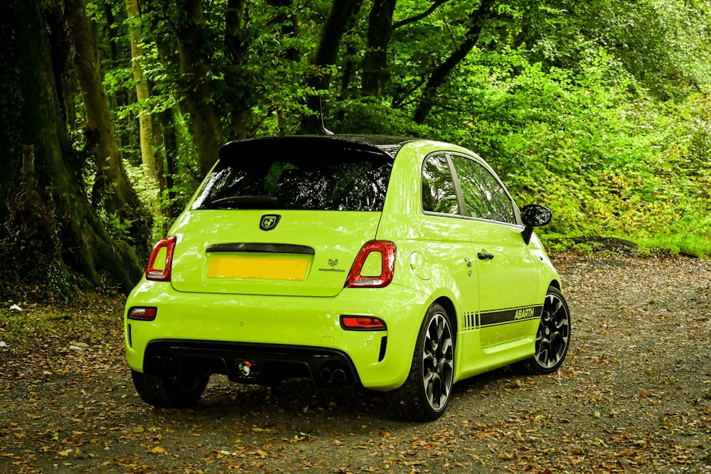 a small green car parked in a wooded area