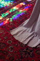 A vibrant, colorful carpet rolled out on a wooden floor, inviting footsteps.