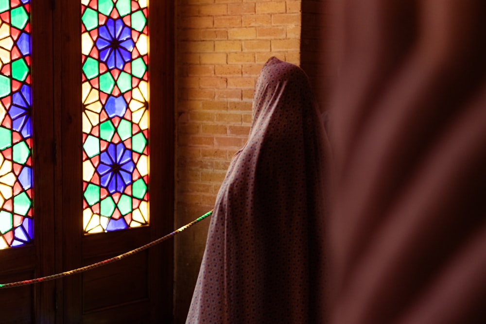a robe hanging in front of a stained glass window