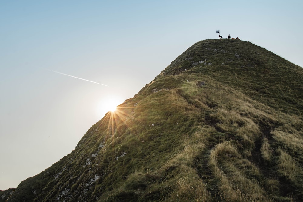 two people standing on top of a grassy hill