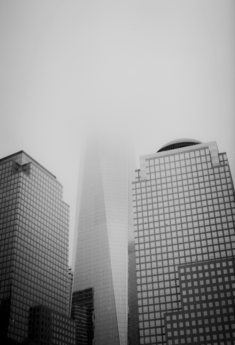 a black and white photo of skyscrapers on a foggy day