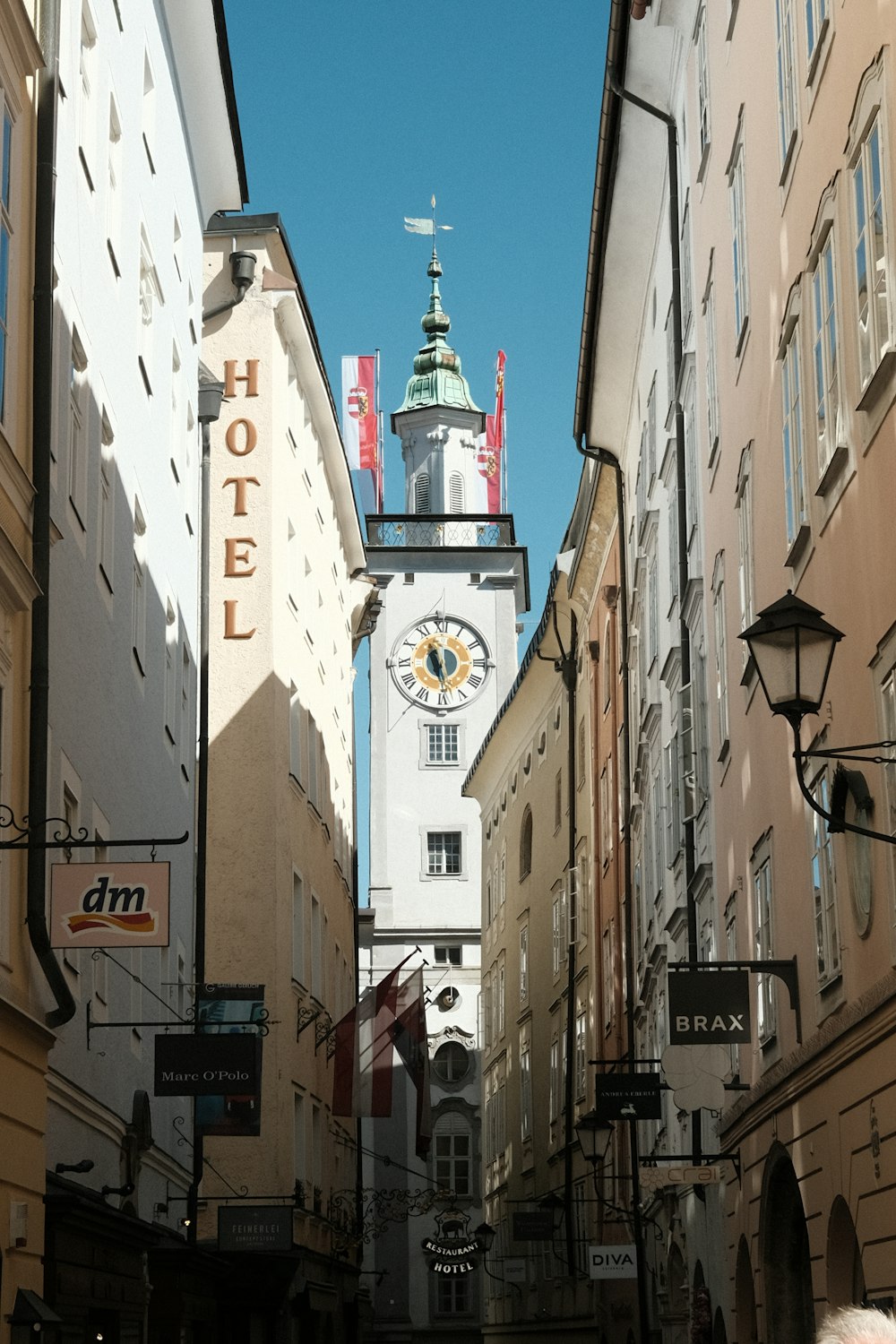 Una stretta strada della città con una torre dell'orologio sullo sfondo