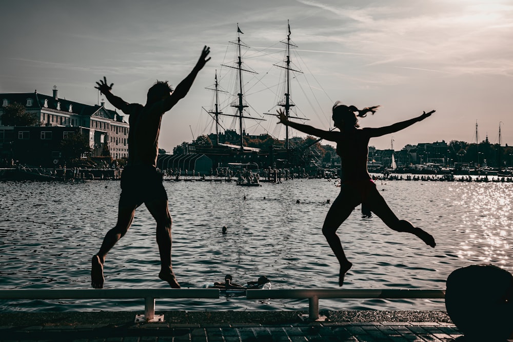 two people jumping off a dock into the water