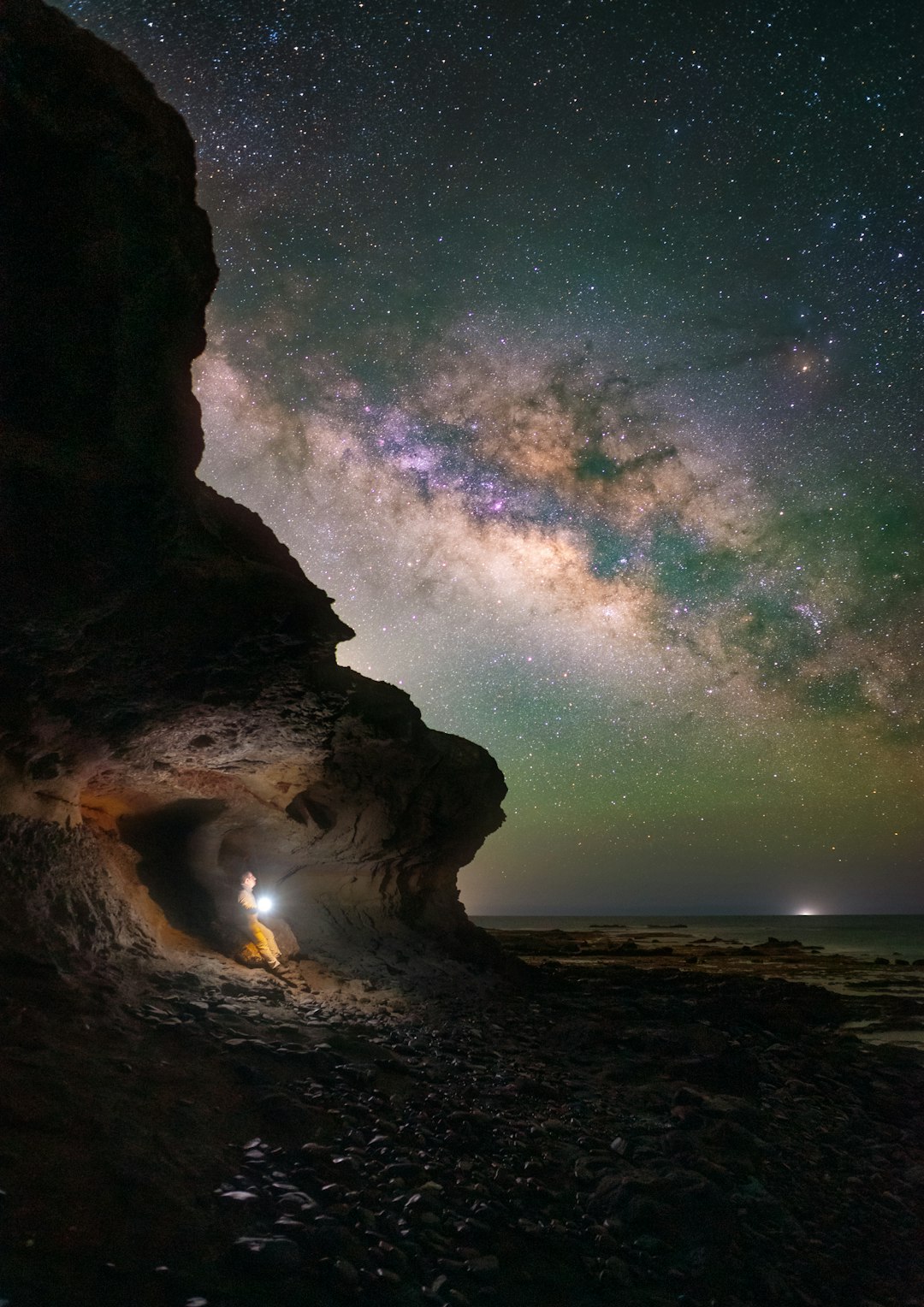 a man standing in a cave under a night sky filled with stars