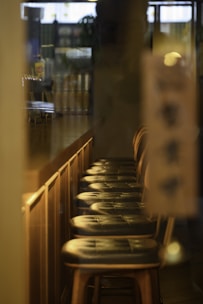 a row of wooden bar stools in a restaurant