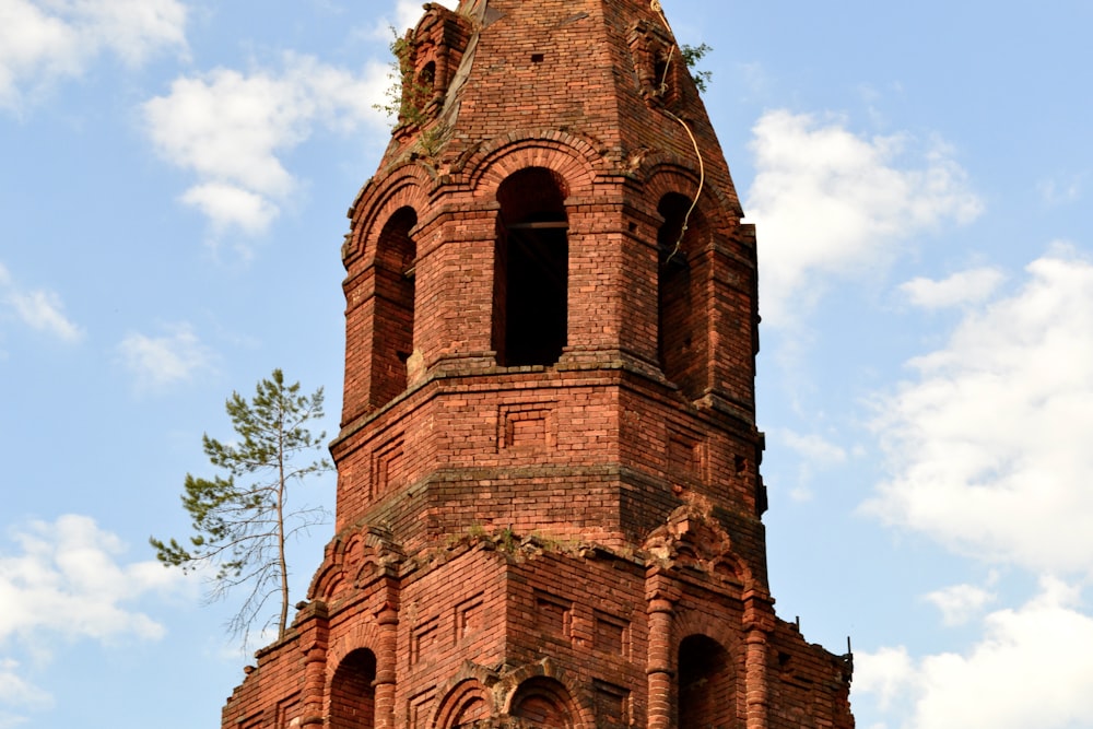 uma alta torre de relógio de tijolos com um relógio em cada um de seus lados