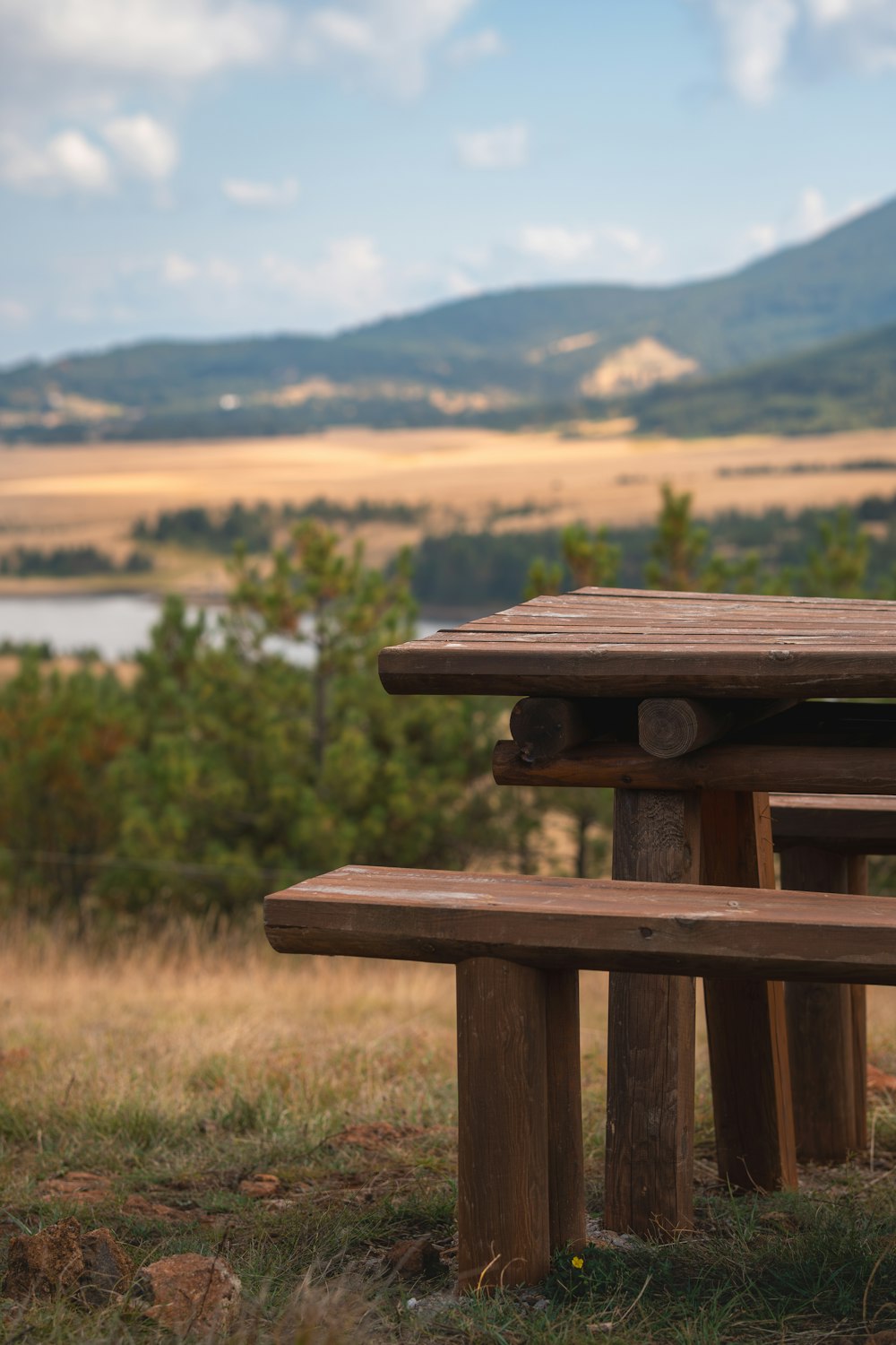 a wooden picnic table sitting on top of a grass covered field